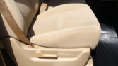 Beige car seat with integrated seatbelt buckle and floor mat visible in the passenger area of a vehicle.