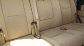 Beige car backseat with three seats and visible seat belts across the middle and right side.