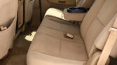 Beige car backseat with a fold-down center armrest featuring two cupholders.